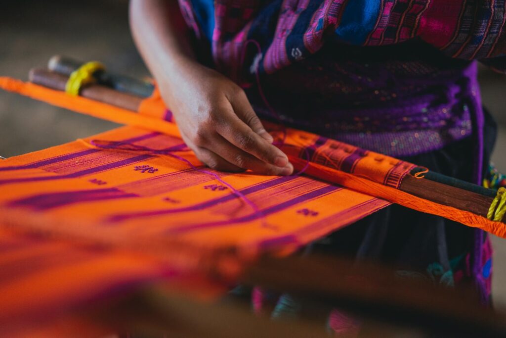 Close-up of a hand crafting vibrant Mexican textile on a loom.